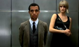 Black man in an elevator standing near a white woman who is clutching her purse